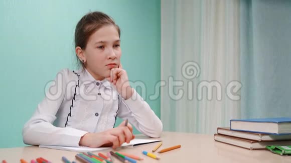 一个穿着白衬衫的年轻女孩在桌子旁做作业视频的预览图