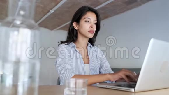 疲惫的年轻商务女性在办公室里用笔记本电脑工作时放松一下视频的预览图