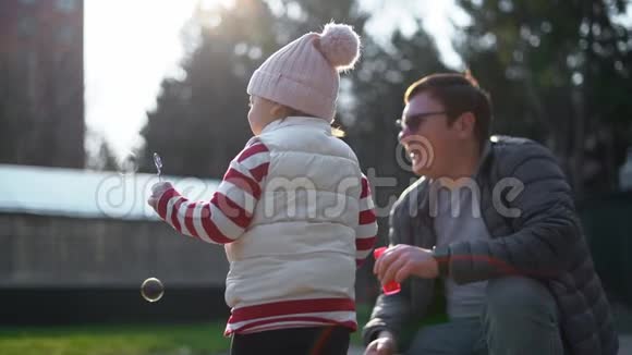 白人男人带着他的孩子在外面吹肥皂泡慢动作幼儿周末活动后院视频的预览图