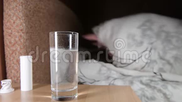 女人在床上辗转反侧等待药片在玻璃杯中溶解视频的预览图