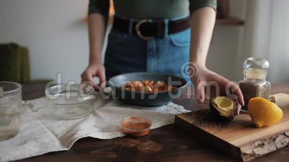 一个年轻的女孩在碗里加入鳄梨和鹰嘴豆在家里做传统的鹰嘴豆特写视频的预览图
