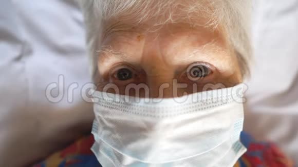 戴着防毒面具的老妇人的肖像躺在床上戴着医用口罩的病老太太视频的预览图