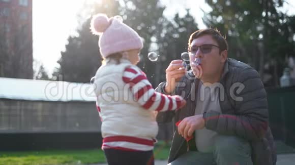 白人男人带着他的孩子在外面吹肥皂泡慢动作幼儿周末活动后院视频的预览图