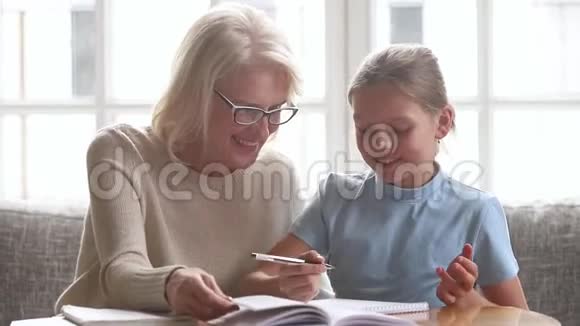 老祖母帮孙女上学的孩子做作业视频的预览图