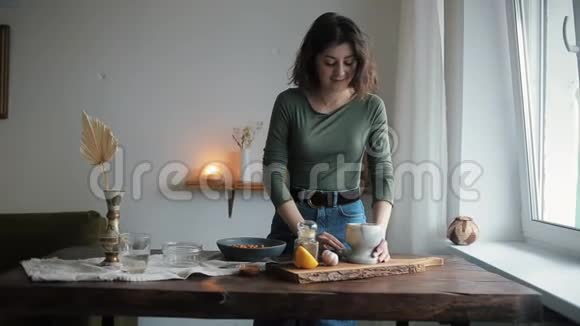 一个可爱的女孩在她的厨房把香料从灰泥到碗与鹰嘴豆煮传统鹰嘴豆视频的预览图