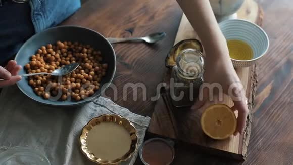 一个女孩的特写镜头她用手把柠檬汁挤到一个碗里放着鹰嘴豆做自制的鹰嘴豆泥视频的预览图