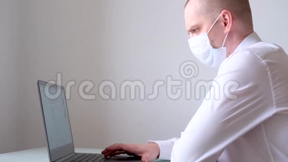 穿着医用口罩和办公室服装白衬衫和领带的人在笔记本电脑上远程从家里谈生意关于视频的预览图