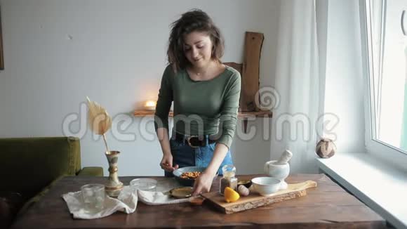 年轻漂亮的女孩在她厨房的一张桌子上混合了烹饪传统鹰嘴豆泥的原料视频的预览图