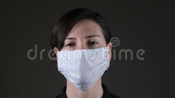 一名高加索妇女摘下一张白色医疗面罩预防传染病冠状病毒的肖像视频的预览图