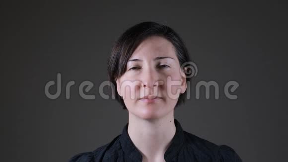 一位白人女性在灰色背景下呼吸的正面肖像视频的预览图