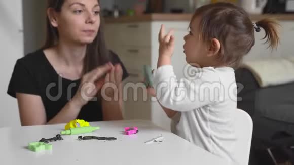 幼妈妈带着蹒跚学步的孩子在家玩面团与幼儿一起家园活动家庭团聚时间视频的预览图