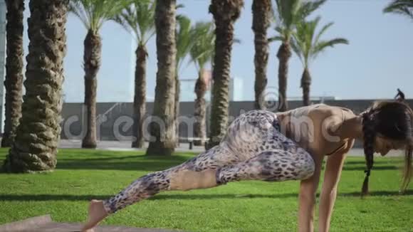女人在公园里伸展身体女孩练习圣人昆迪亚姿势瑜伽垫视频的预览图