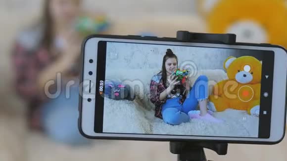 智能手机屏幕的特写两个姐妹带领一个视频博客两个十几岁的女孩一边说话一边看着视频的预览图