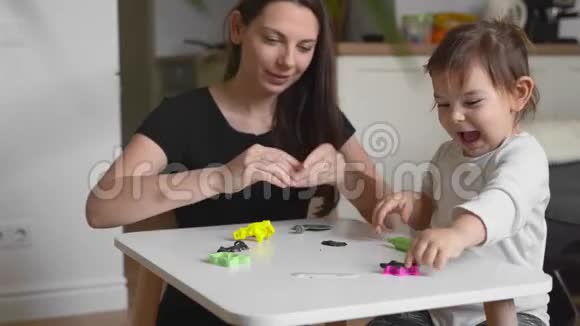 幼妈妈带着蹒跚学步的孩子在家玩面团与幼儿一起家园活动家庭团聚时间视频的预览图