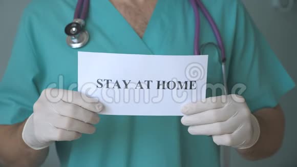 医生手里拿着一张照片上面写着冠状病毒流行期间呆在家里医药展海报视频的预览图