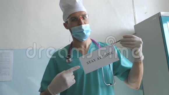 医生正拿着一张刻有铭文的照片在冠状病毒流行期间呆在家里Medic显示海报有吸引力视频的预览图