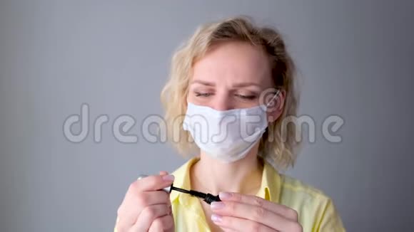 柯莉金发快乐女孩在医用防护面具上涂睫毛做化妆看着摄像机妇女反对视频的预览图