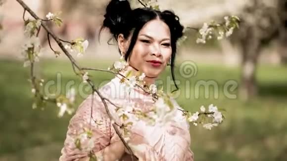 从盛开的花枝上观赏迷人的亚洲女士远望花园视频的预览图