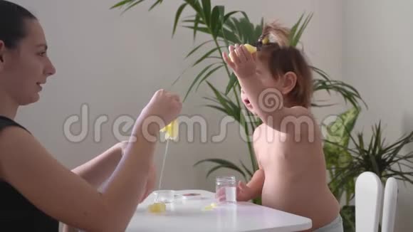 幼儿女孩和妈妈在玩黄色粘稠的黏液家园活动幼儿在家运动技能发展视频的预览图