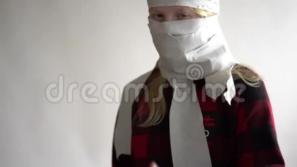 有趣的视频由于冠状病毒的流行而被隔离戴着面具的女孩用卫生纸在灰色的视频的预览图
