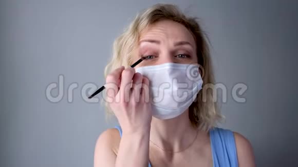 4kCurly金发快乐女孩在医用防护面具做眼妆应用眼影看着摄像机妇女视频的预览图