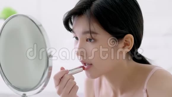 美丽的年轻亚洲女人涂粉红口红嘴型亮闪闪视频的预览图
