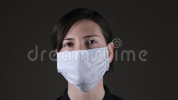 一名白人妇女戴着白色医疗面罩以抵御传染病冠状病毒的肖像视频的预览图