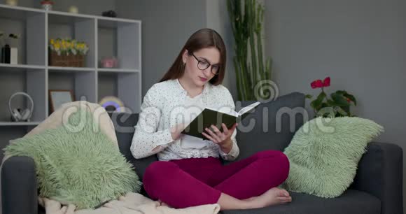 年轻学生读一本书美丽的黑发女人在家的床上看书视频的预览图