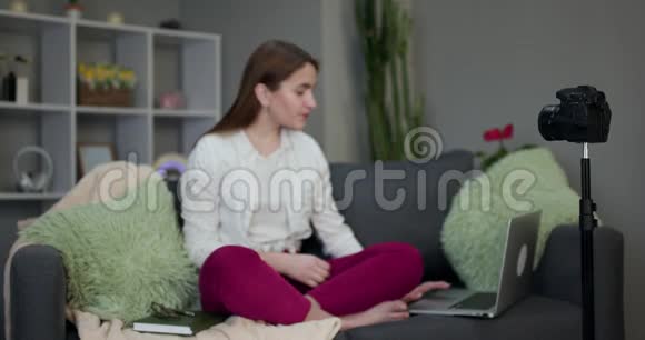 年轻的少女vlogger在家里的沙发上做一个视频流人和技术年轻女性作为vlogger工作视频的预览图
