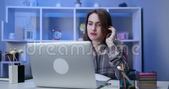 认真的女学生戴着耳机在网上学习与网络老师学习语言看笔记本电脑专注视频的预览图