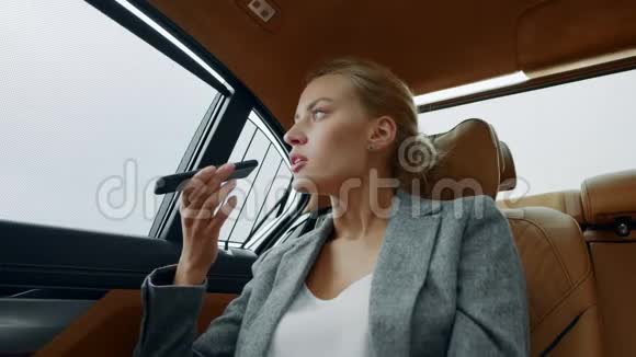 关闭严肃的商务女性在汽车上的手机上记录语音信息视频的预览图