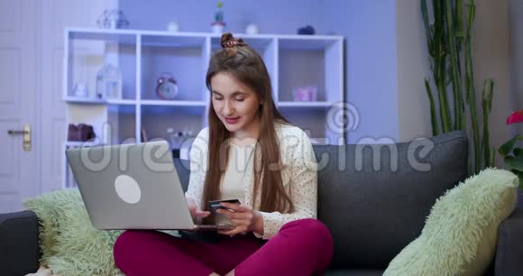 女人用笔记本电脑连接用信用卡做网上购物年轻女孩在网上买东西视频的预览图