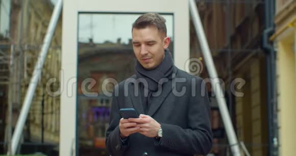 现代办公中心附近使用智能手机的人的肖像在社交网络里和他的朋友聊天看上去视频的预览图
