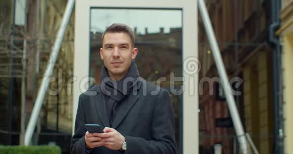 现代办公中心附近使用智能手机的人的肖像在社交网络里和他的朋友聊天看上去视频的预览图