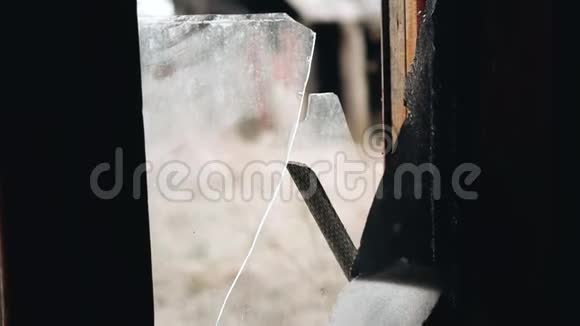 男孩从窗框上拆下破碎的玻璃被遗弃的房屋视频的预览图