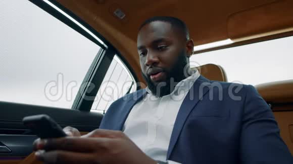 非洲商人看智能手机看汽车一个拿着电话的黑人视频的预览图