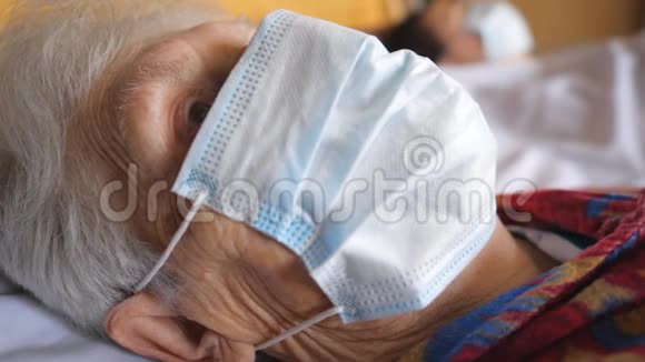 把戴防护面罩的老妇人的脸闭上防止病毒带着悲伤的视线和医用口罩的病妇视频的预览图