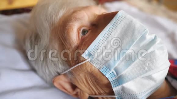 奶奶戴着医用防护口罩的病毒肖像可怜的女士躺着看着摄像机视频的预览图