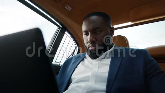 肖像非洲男子工作与笔记本电脑坐豪华车的非洲男人视频的预览图