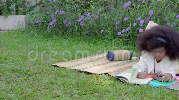 快乐的非洲家庭孩子们躺在花园里看书或写作孩子们去野餐视频的预览图