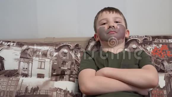 不高兴的男孩坐在沙发上汉明双臂交叉脸上画着画视频的预览图