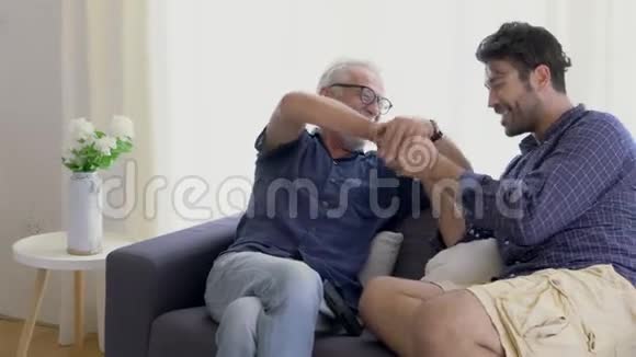 幸福的家庭和年长的父亲和儿子交谈亲吻手与快乐的沙发视频的预览图