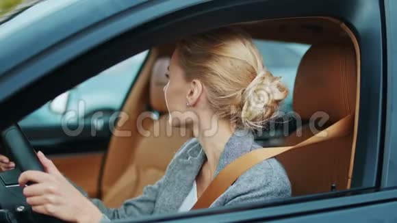 女商人坐着车在方向盘上跳舞坐在车里的微笑女孩视频的预览图