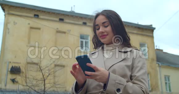 吸引人的年轻女人在市中心用电话和朋友聊天女孩在户外用手机慢动作视频的预览图