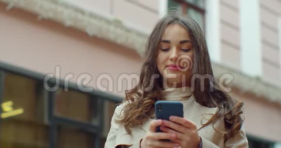 吸引人的年轻女人在市中心用电话和朋友聊天女孩在户外用手机慢动作视频的预览图