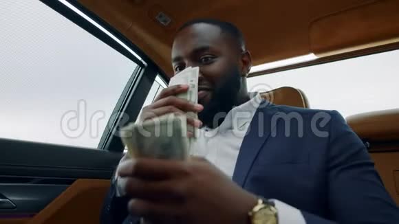 特写非洲男人在车里闻着美元坐着有钱的男人视频的预览图