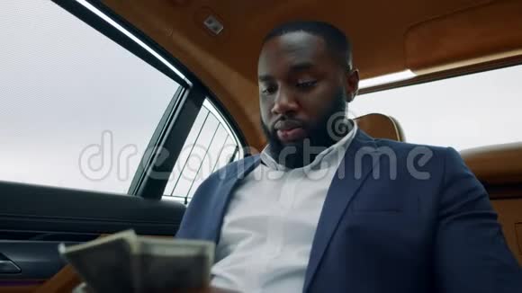 商人在车上数钱的肖像在车里闻钱的非洲人视频的预览图