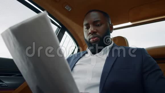 特写非洲男人在豪华车上看文件商人扔报纸视频的预览图