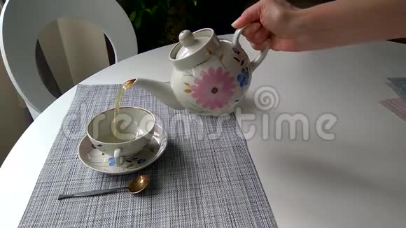 女孩把茶倒进桌子上的杯子里视频的预览图