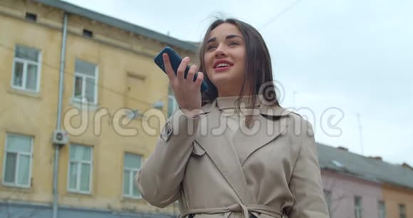 女士使用智能手机语音录音功能在线在城市街道与移动助理交谈女孩使用视频的预览图